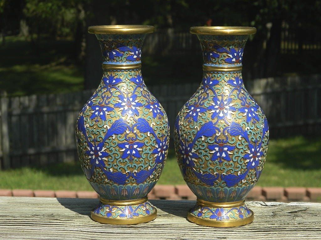 Two blue-and-gold ornate vases on a wooden surface outdoors