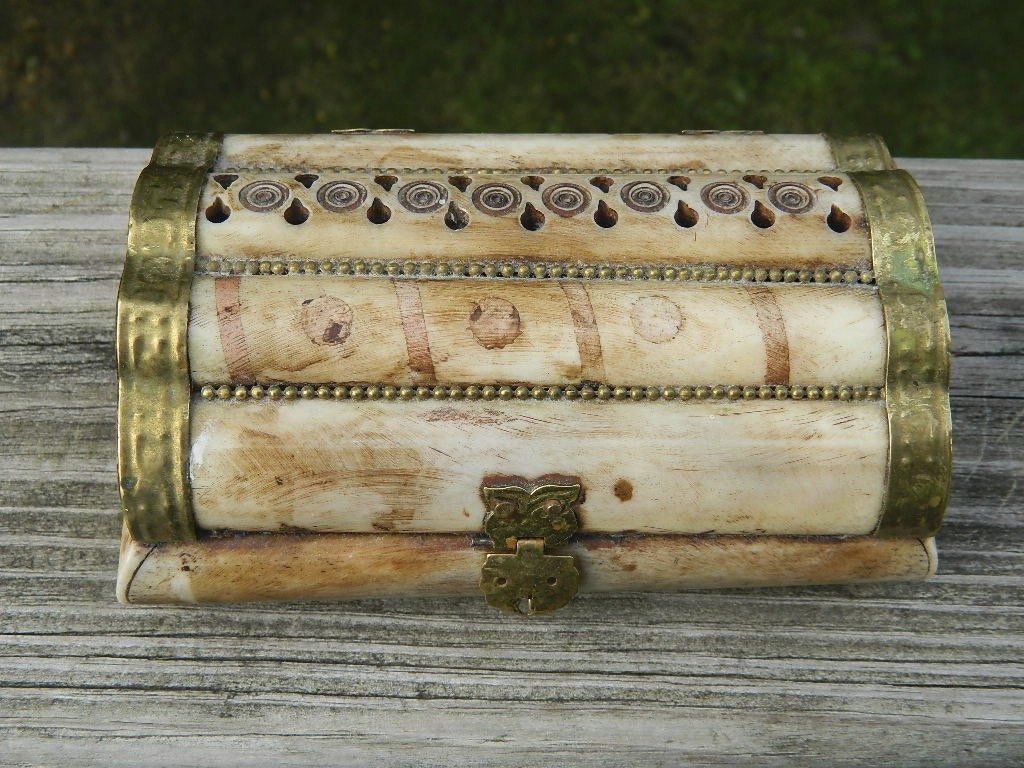 Antique ivory and gold inlaid jewelry box with floral patterns on a wooden surface