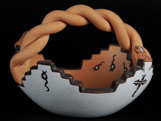 Cracked ceramic bowl with a twisted tan rim and a sad face painted on the broken surface