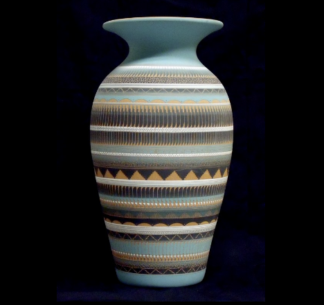 Tall light blue vase with horizontal brown, cream, and gray geometric patterns on a dark background