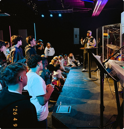 Audience watching a speaker on a dimly lit stage in a small venue