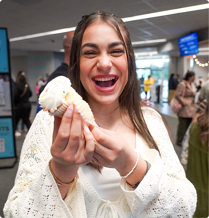 Smiling woman holding a cupcake in a bright indoor setting