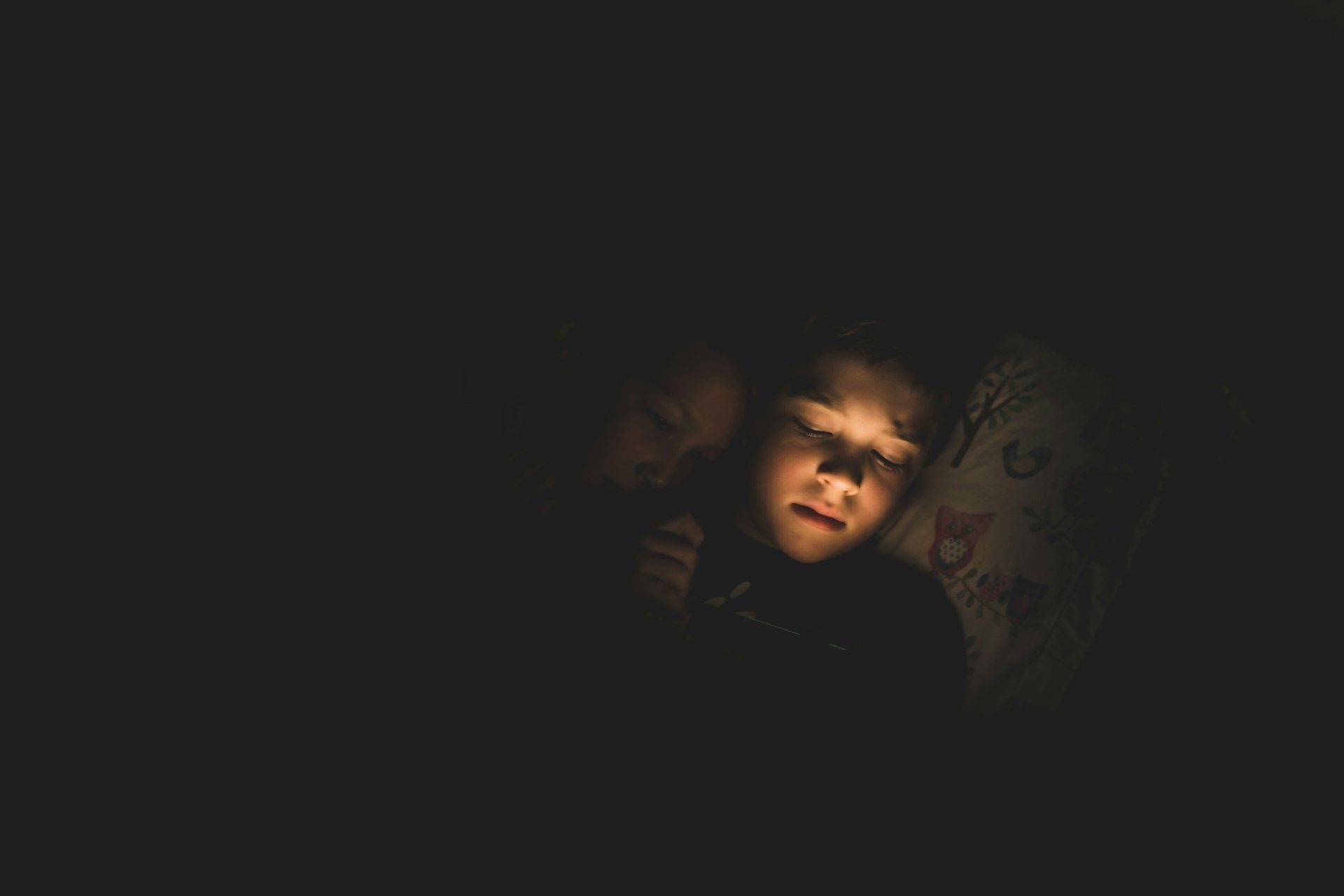 kid using gadgets in bed