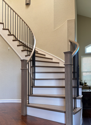 Curved modern staircase with stained wooden treads, square handrailing and plain iron balusters with painted skirtboards and risers