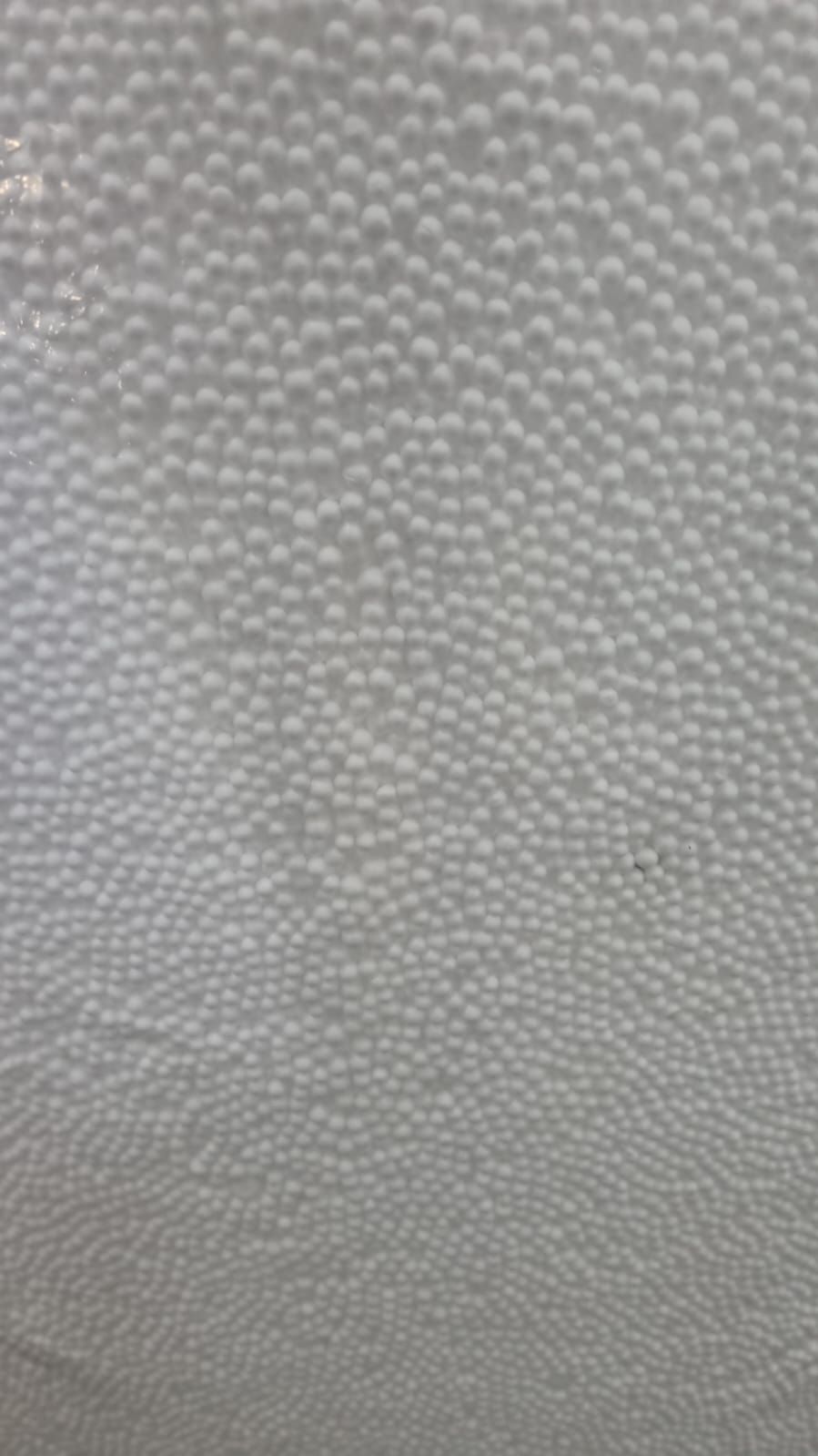 Close-up of a white surface with many small, round bumps creating a textured pattern.