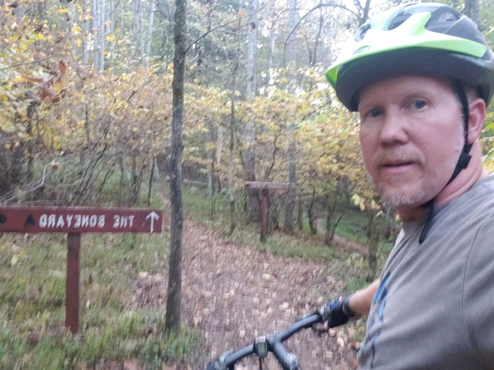 Man on bike at trail entrance; sign points to 