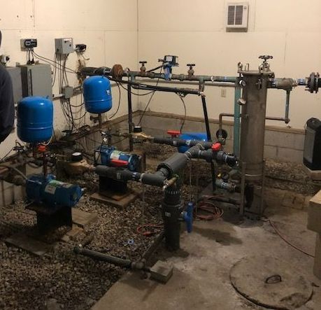 A man is standing in a room with a lot of pipes.