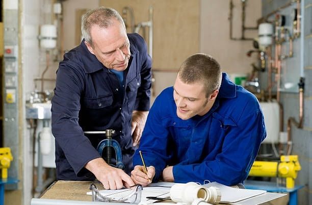 Two workers in blue shirts reviewing plans at a workshop table