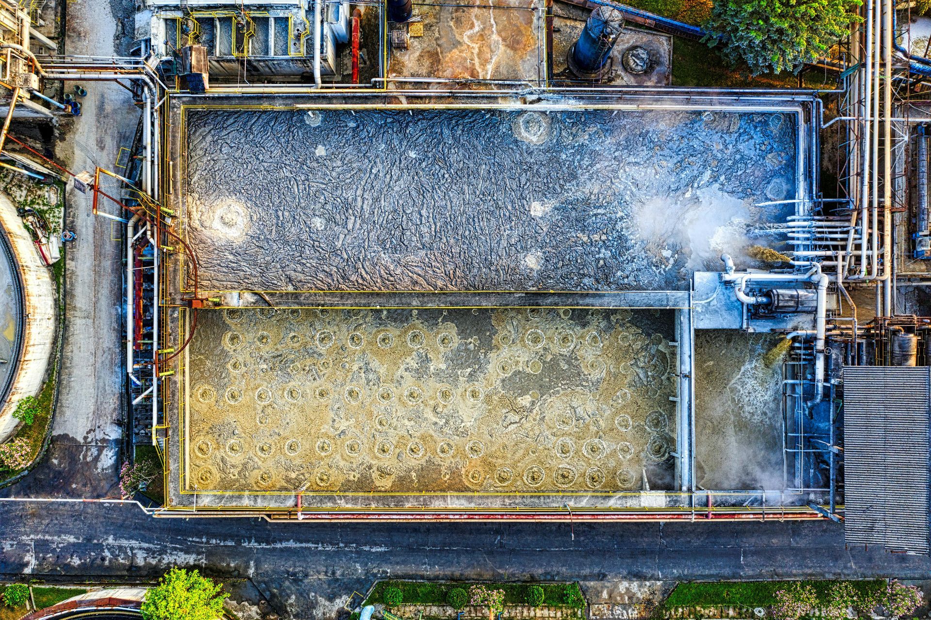 Aerial view of a rectangular industrial water tank with two sections, pipes, and surrounding machinery
