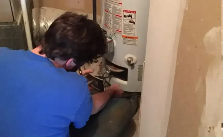 Two people inspect plumbing under a kitchen sink during a home repair visit