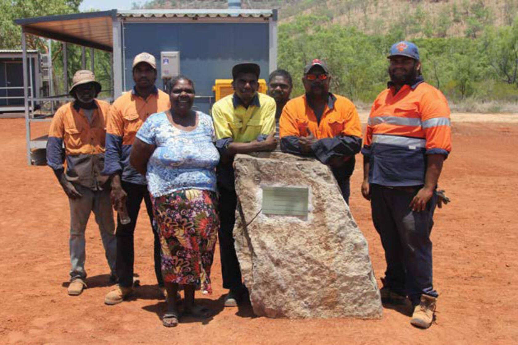 A group of people standing next to a large rock.