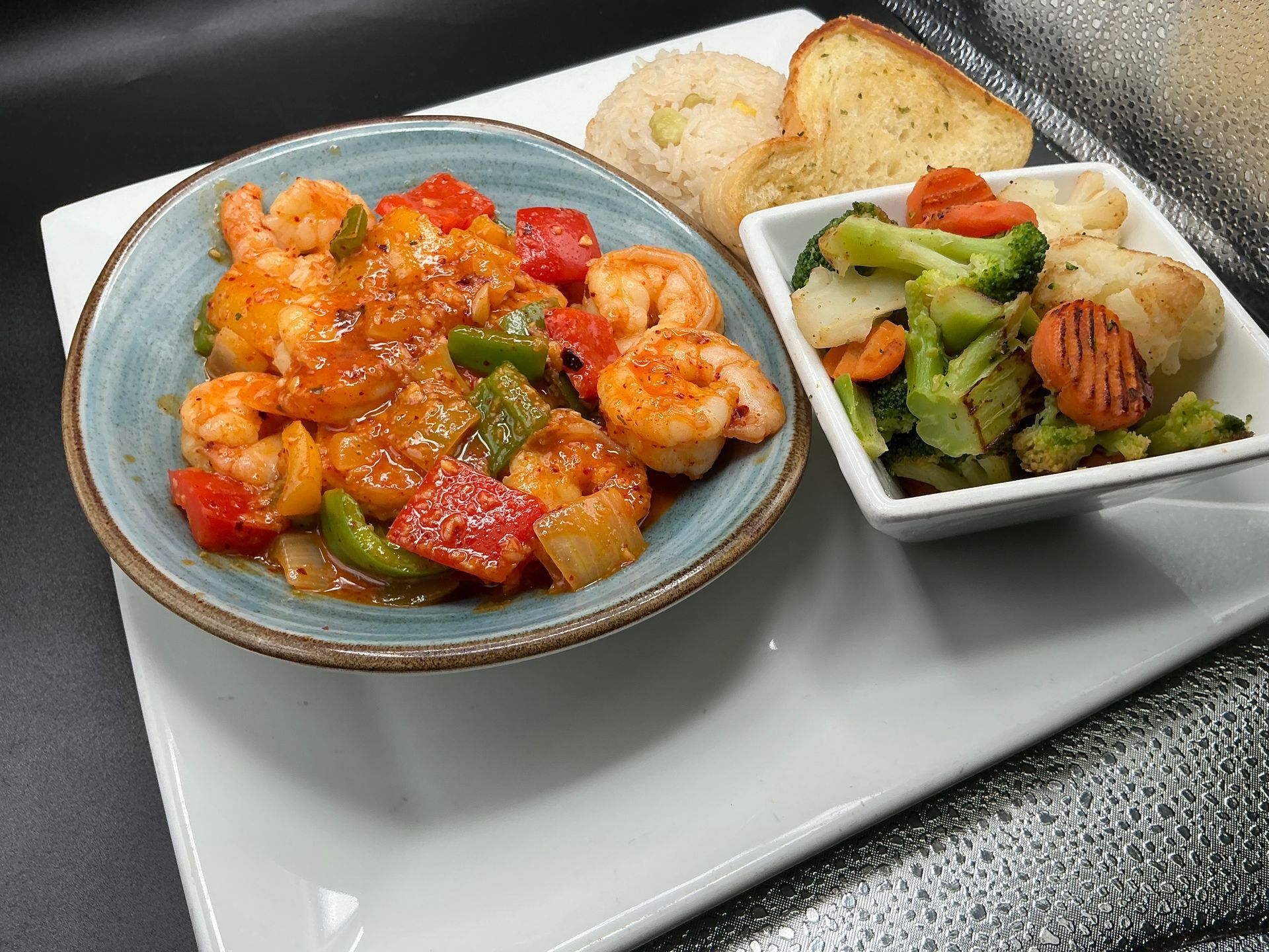 Shrimp with vegetables and sides on a white plate.