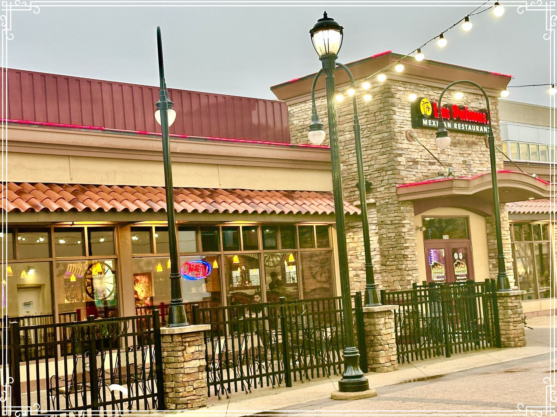 Restaurant exterior with stone facade, string lights, and street lamps.