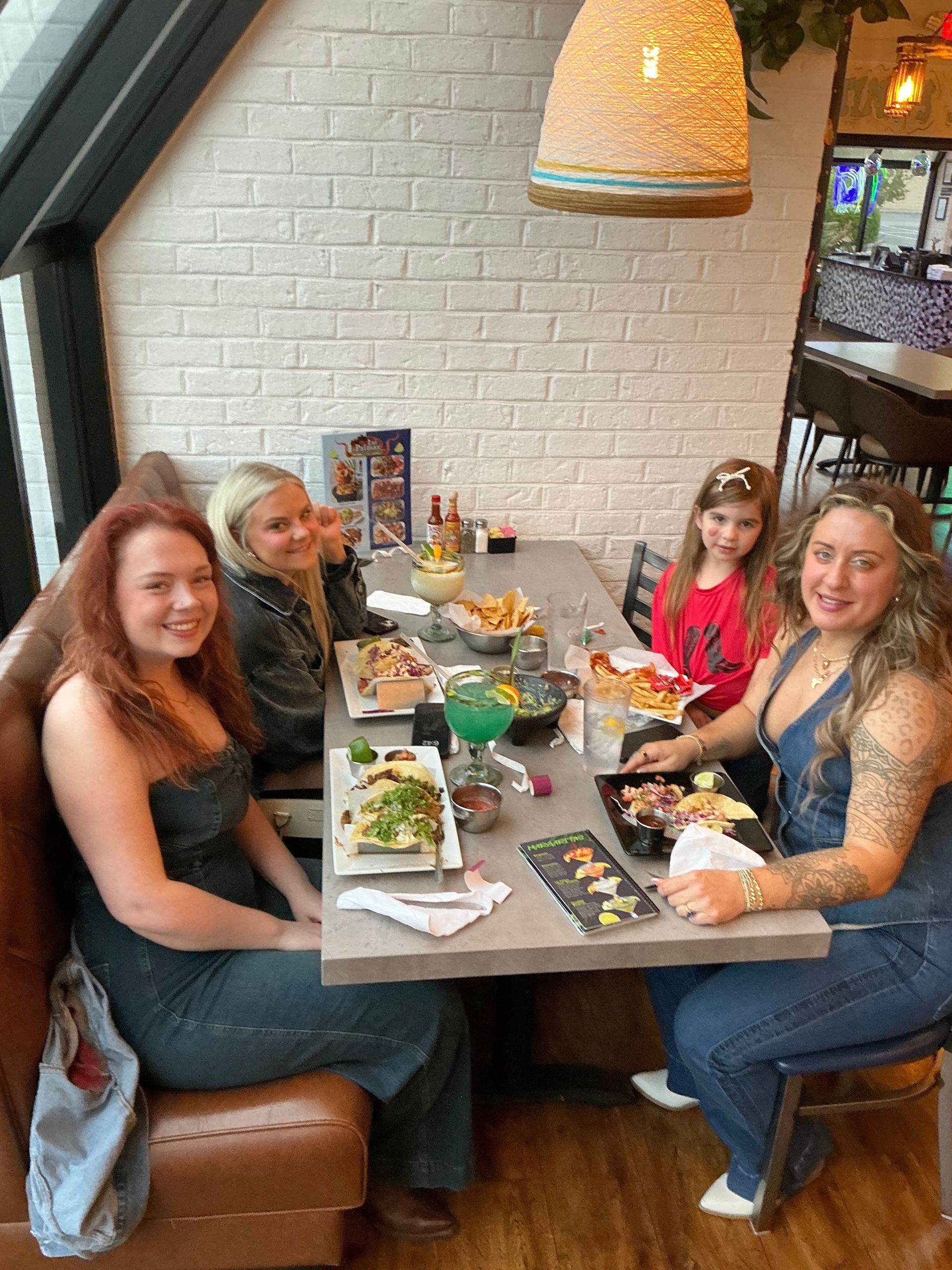 Four people seated at a table in a restaurant. They are eating and smiling.