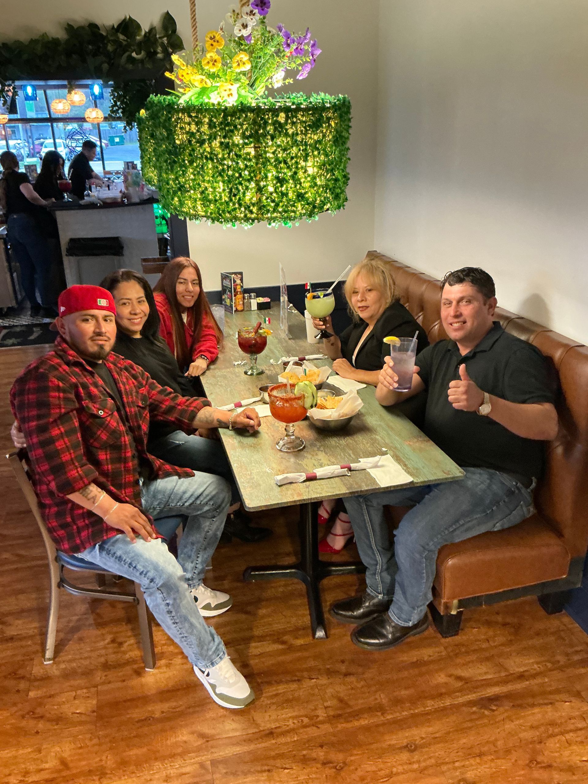 A group of people at a restaurant, drinking cocktails at a table.