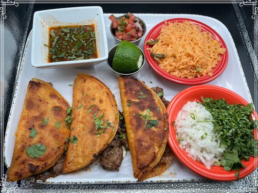 Birria tacos with consommé, rice, salsa, lime, onions, cilantro.
