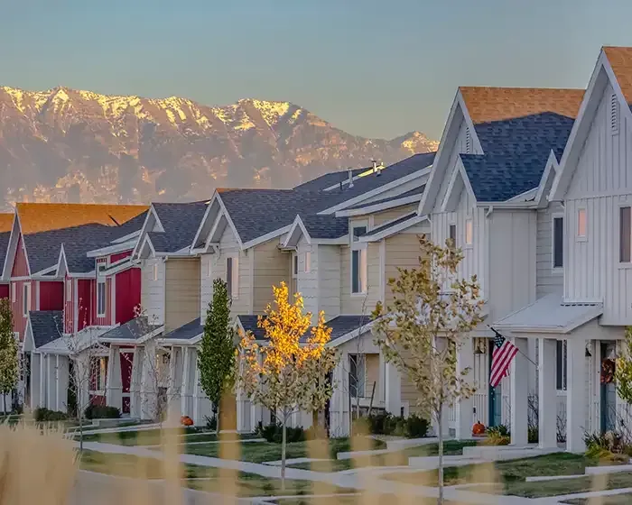 Suburban homes along a wet street with mountains glowing in the sunset background.