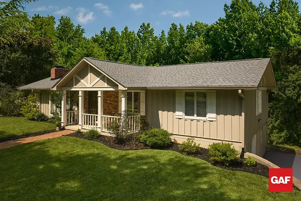 Single-story beige house with front porch, white trim, and green lawn under clear blue sky