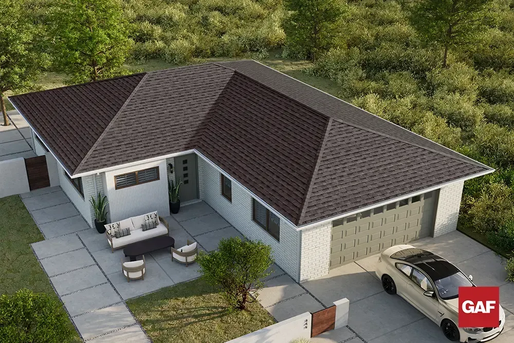Aerial view of a modern single-story house with a dark roof, patio seating, and a driveway.