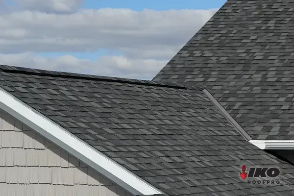 Gray shingled roof with white trim under a cloudy blue sky