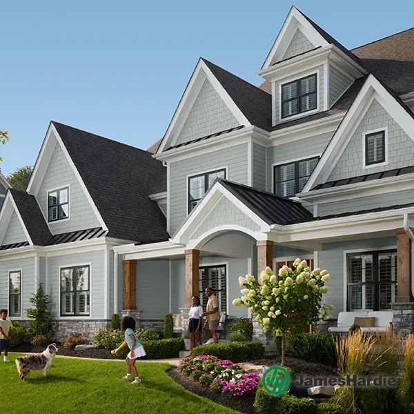 Modern gray house with a manicured lawn, flowers, and people playing outside in the yard