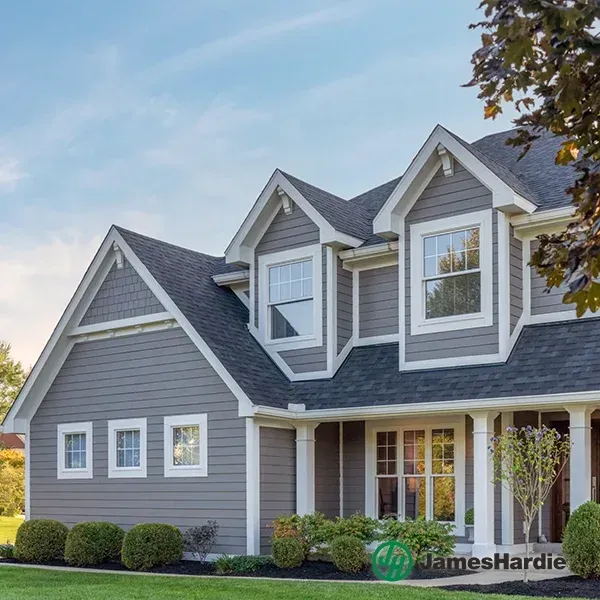 Gray suburban house with white trim, gabled roof, and front porch under a blue sky