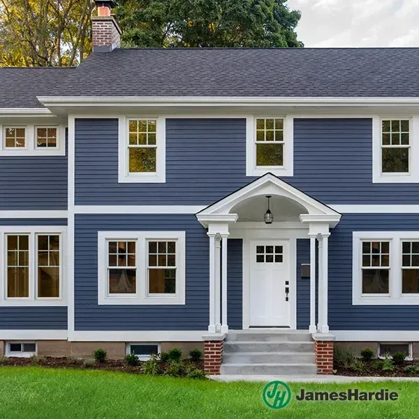 Blue two-story house with white trim, front porch, and green lawn