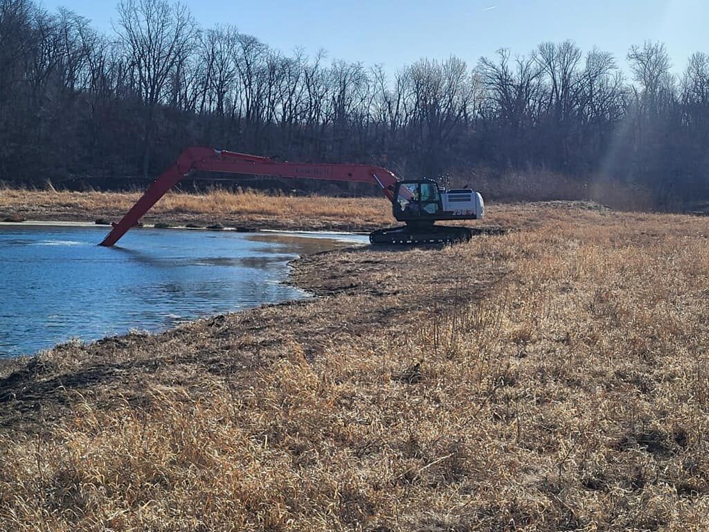 A large excavator is working on a body of water.