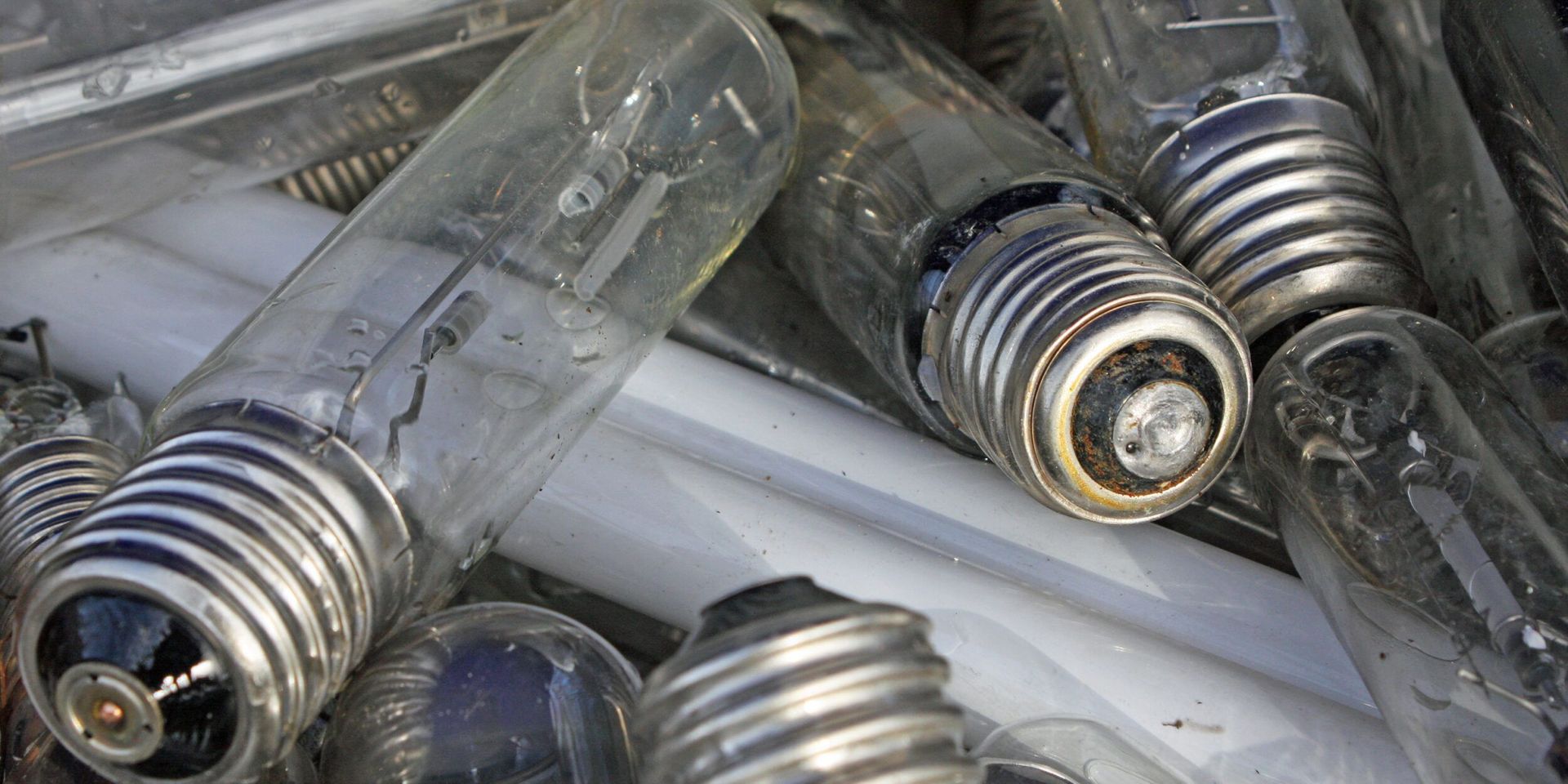Close-up of a pile of used light bulbs, with glass and metal components.