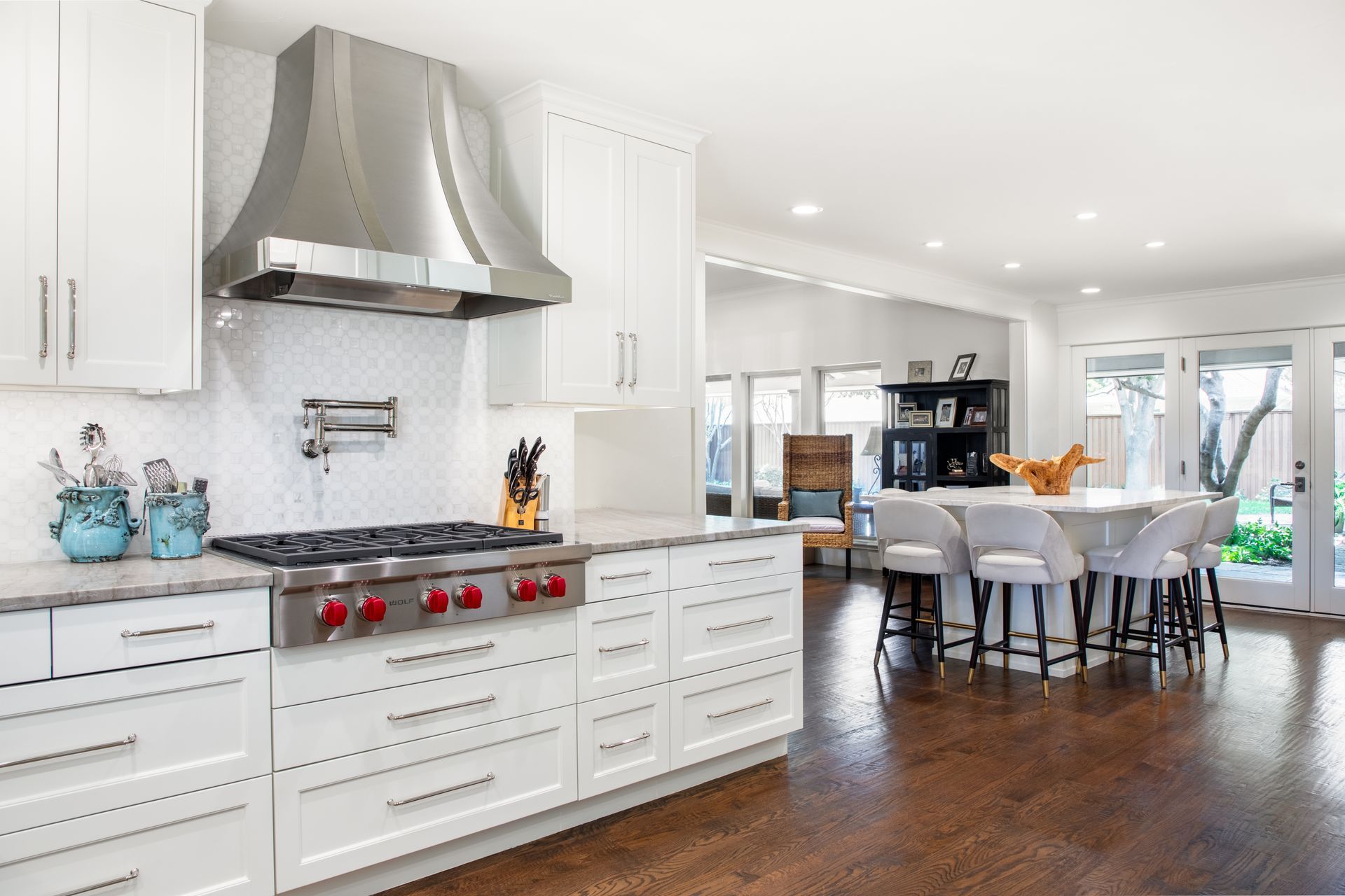 A bright kitchen with white cabinetry, a stone accent wall, a central island with stools, and an adjacent dining area.