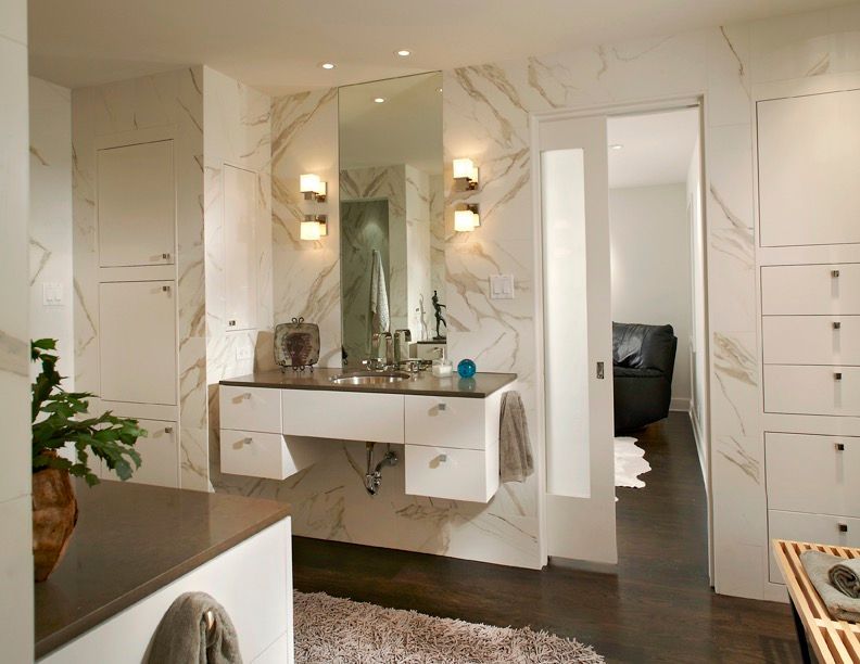 Modern bathroom with white and marble walls, floating vanity, large mirror, and open door to a bedroom.Highland Park Bathroom