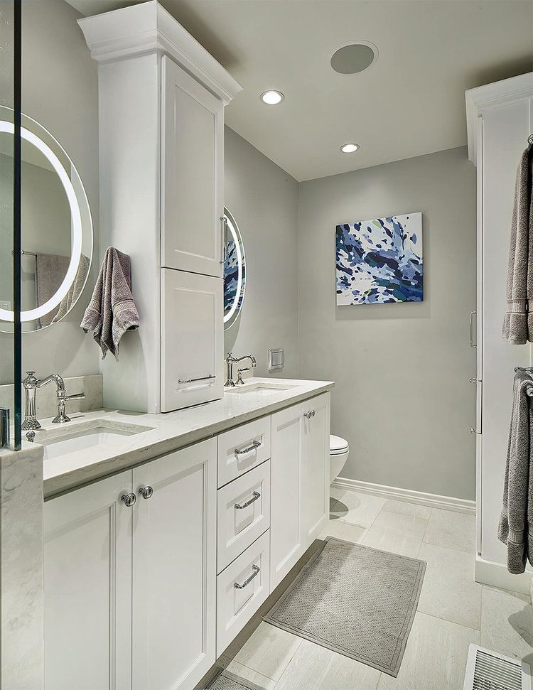 White bathroom with double vanity, tall storage cabinet, grey walls, art, and rug. Northwood Hills Bathroom renovation.