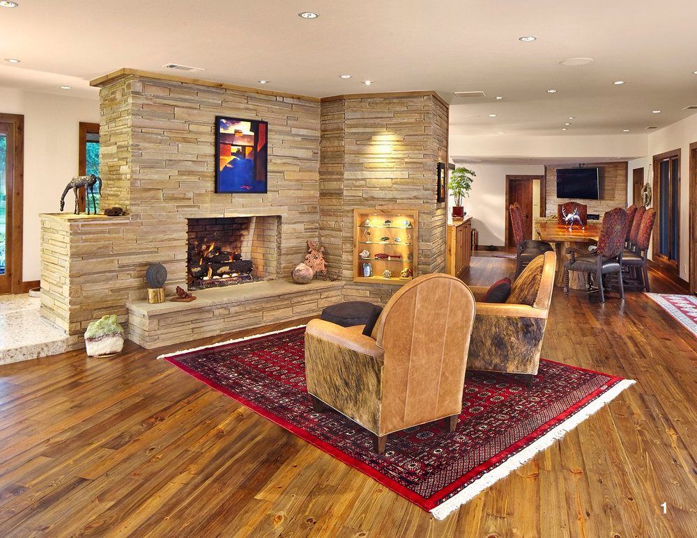 Cozy living room with stone fireplace, wooden floor, area rug, and armchairs. Highland Park living room renovation.