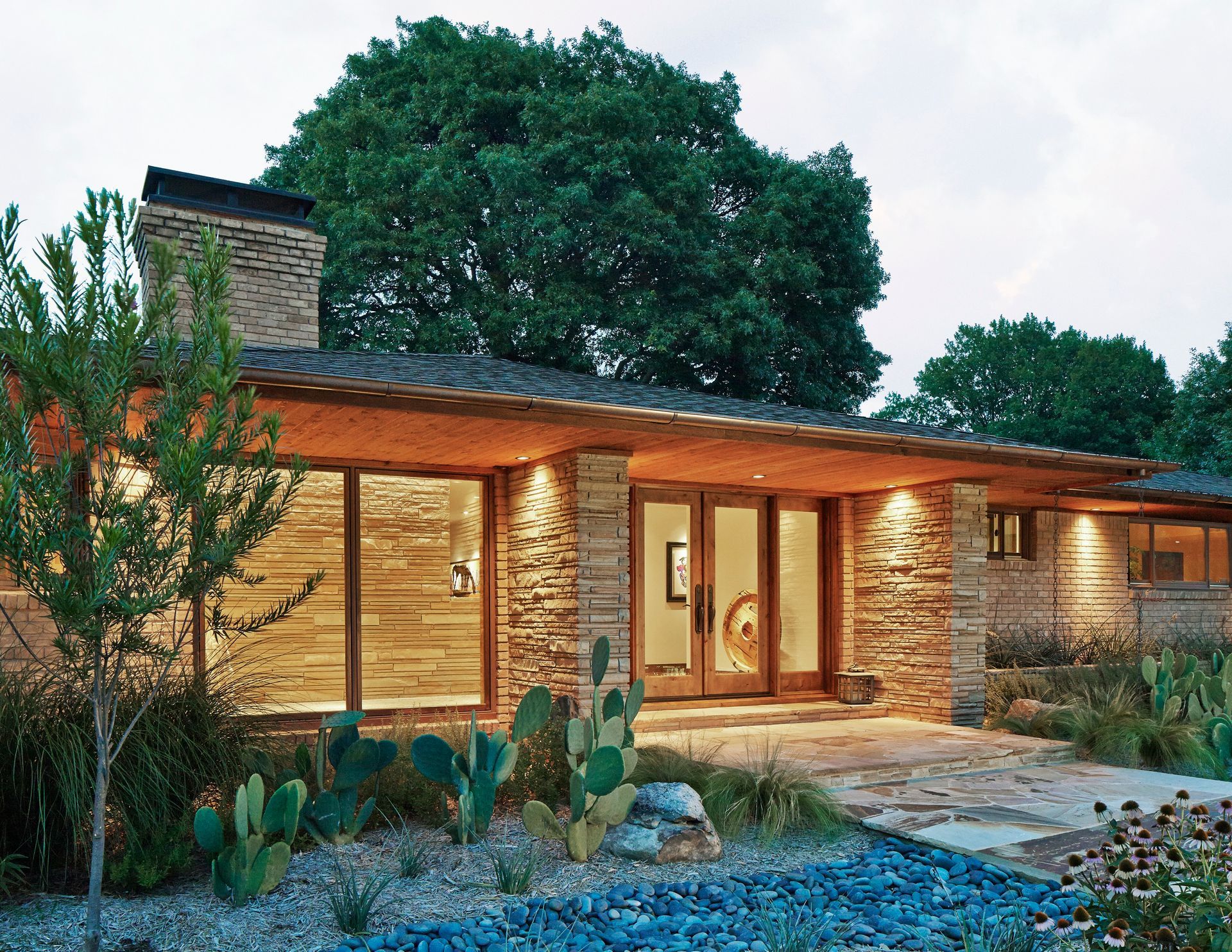 Modern home exterior with stone facade, large windows, and landscaped yard. Richardson exterior update.