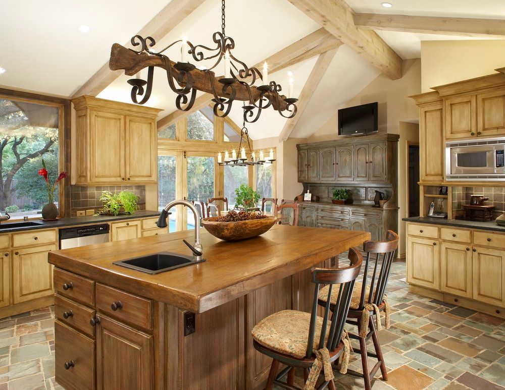 Rustic kitchen with wood cabinets, island, and vaulted ceiling; stone floor.