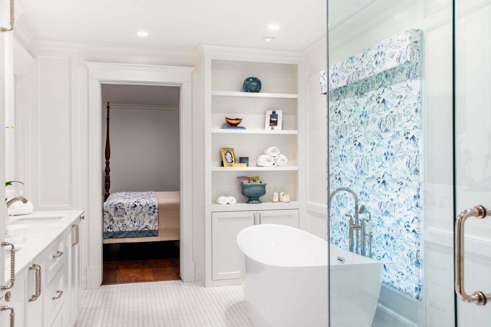 White bathroom with built-in shelves, a soaking tub, and a glass-enclosed shower with a patterned wall.