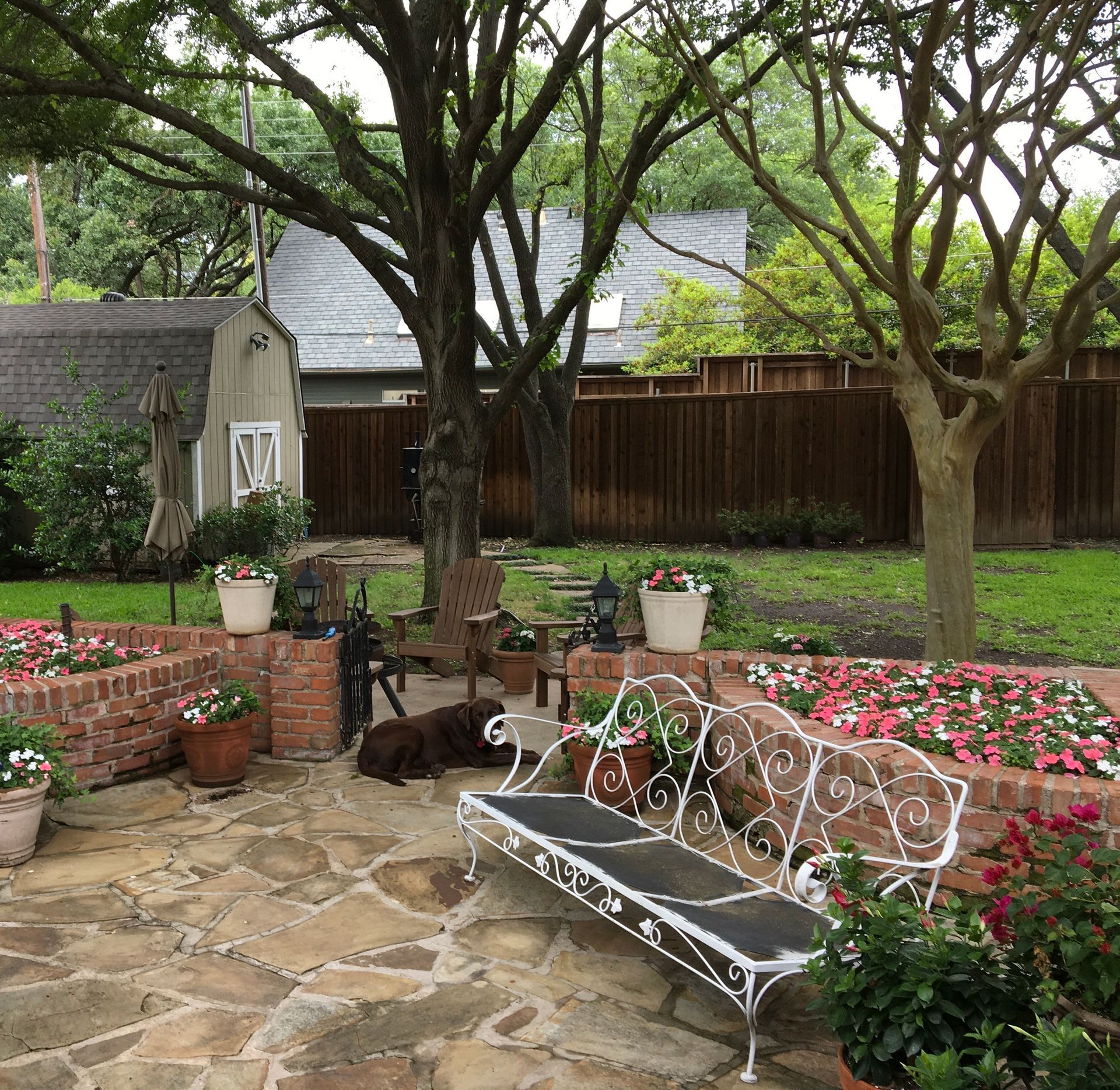  a stone courtyard garden with trees, benches, and flower beds after rain