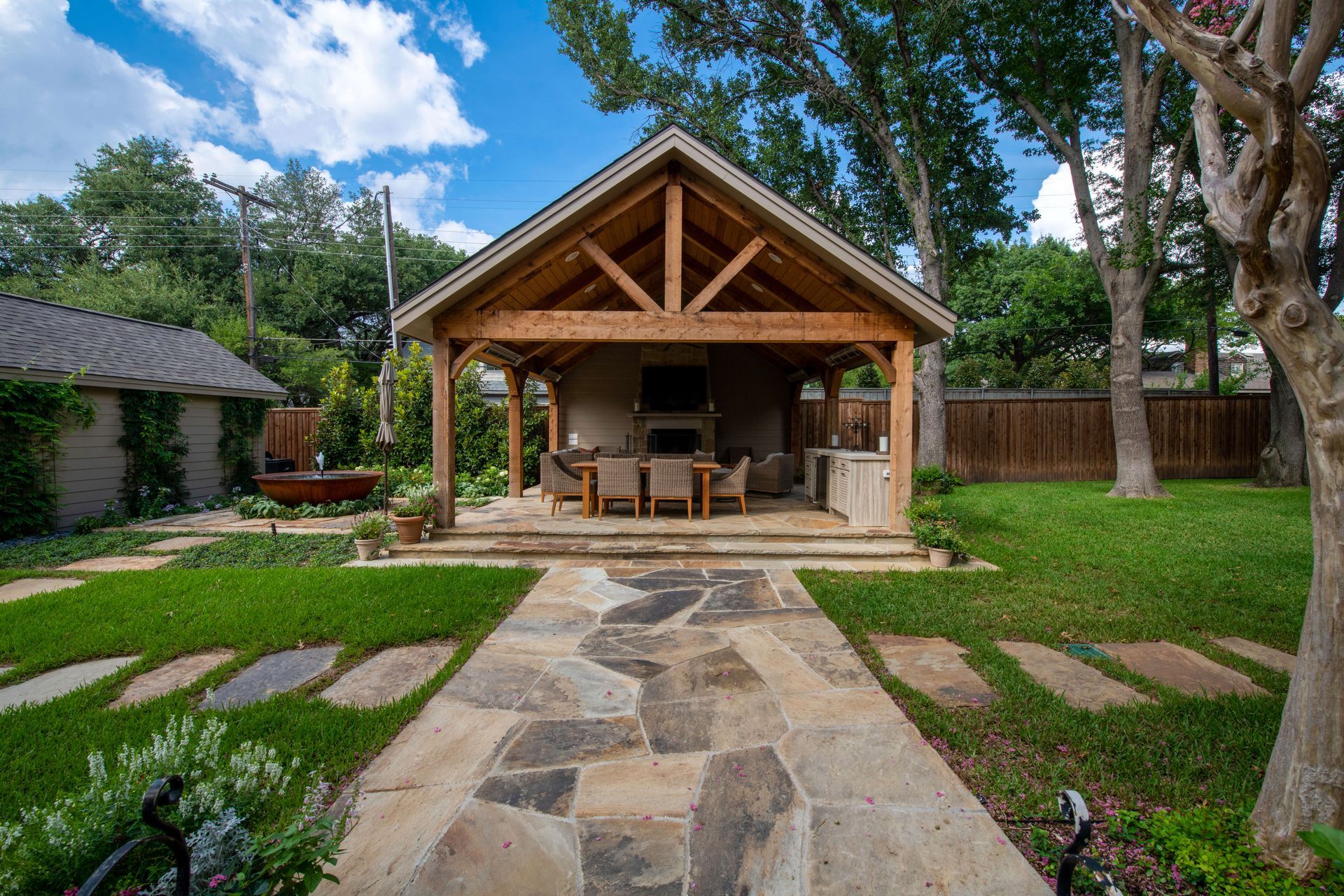 Outdoor kitchen with a green ceramic grill and stainless steel drawers next to a backyard pool and hot tub.