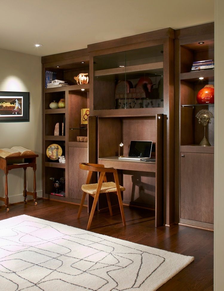 Built-in desk and bookshelves in a home office. Dark wood, with a chair and laptop. Highland Park office renovation.
