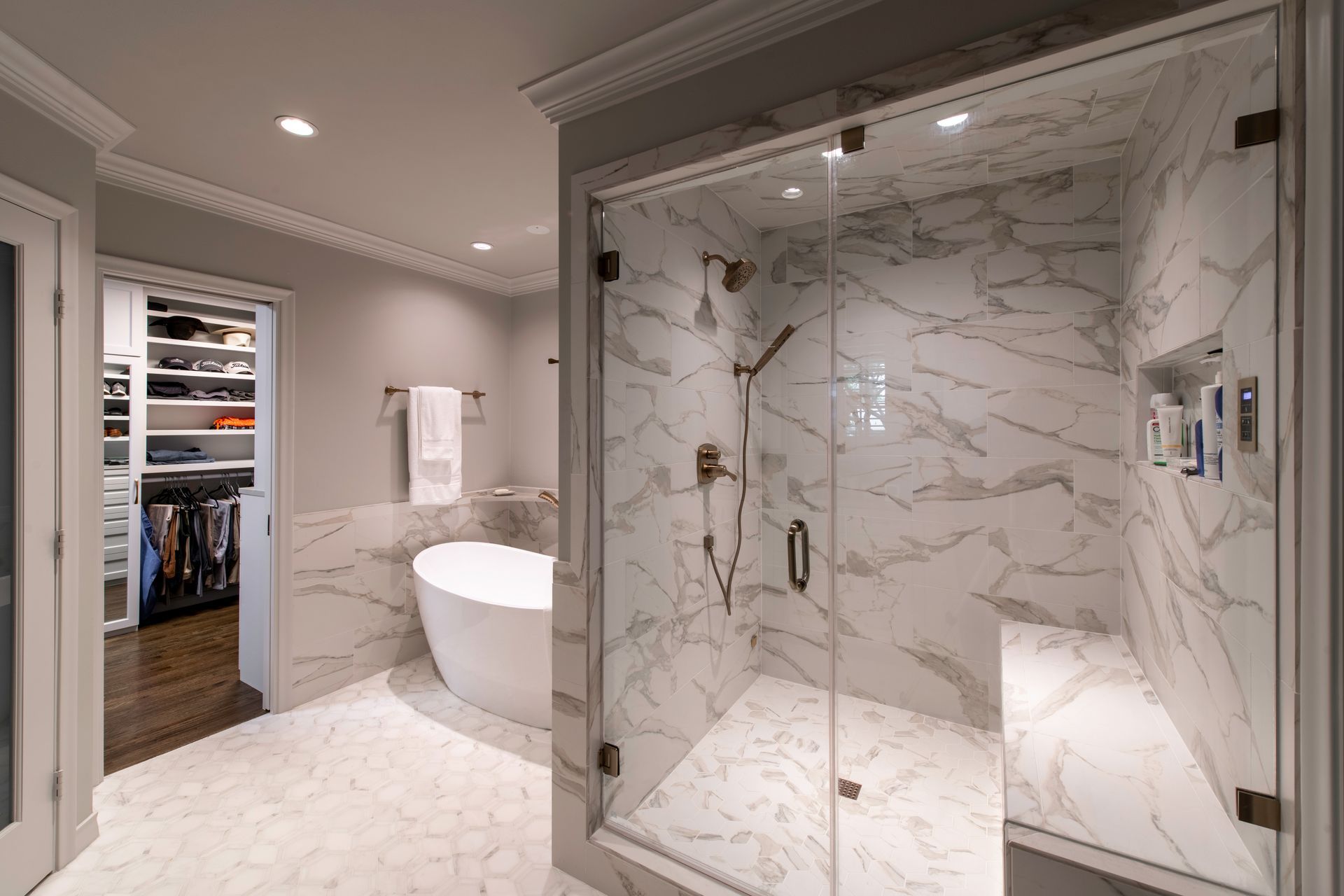 Luxury marble bathroom with glass shower, soaking tub, and open walk-in closet beyond