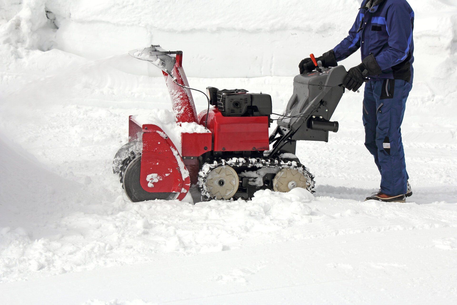 A man is pushing a snow blower through the snow.