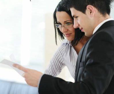 a man and a woman are looking at a piece of paper .