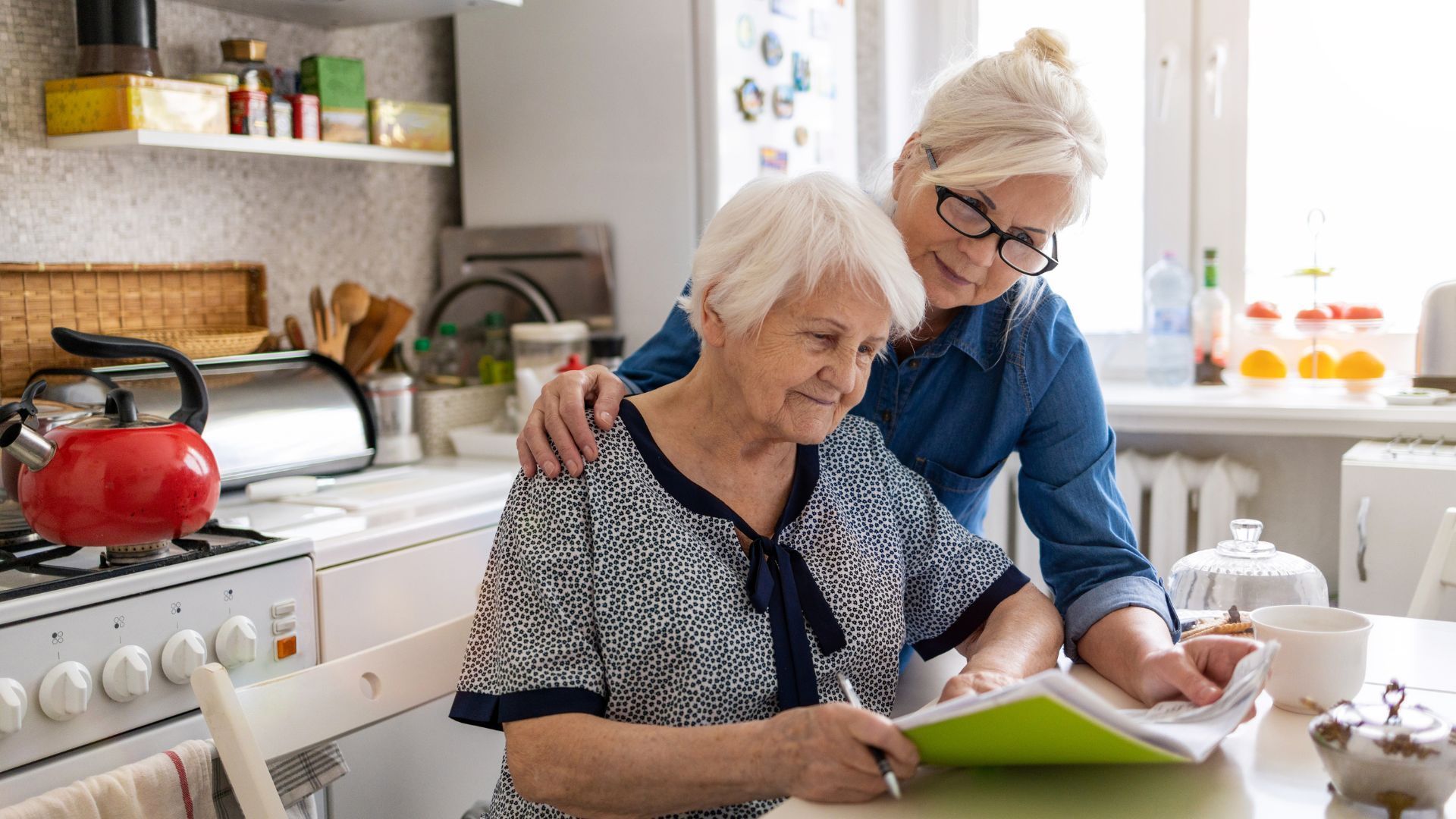 an elderly woman is sitting at a table with a caregiver .