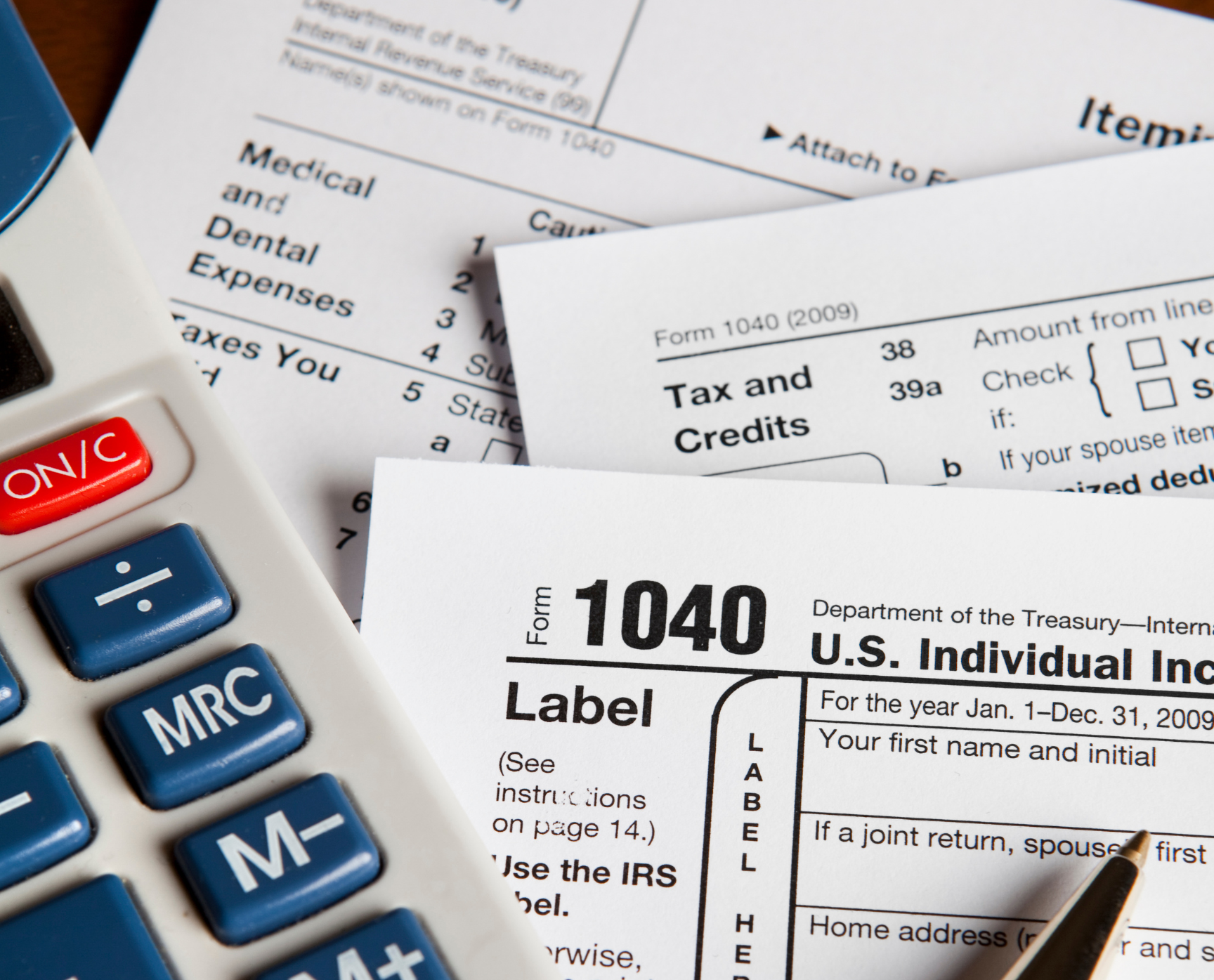 A 1040 tax form is laying on top of a calculator