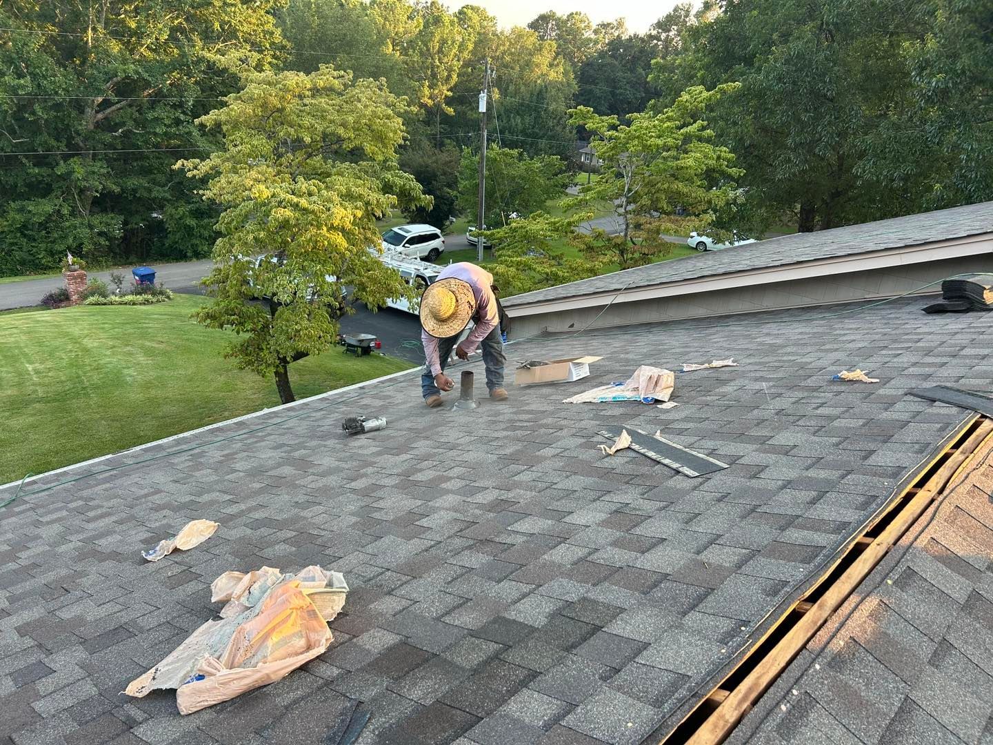 Two roofers working on a house roof under a clear blue sky.