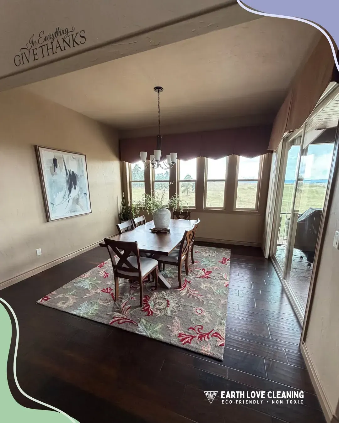 Dining room with wooden table, chairs, patterned rug, and large windows overlooking a bright view.
