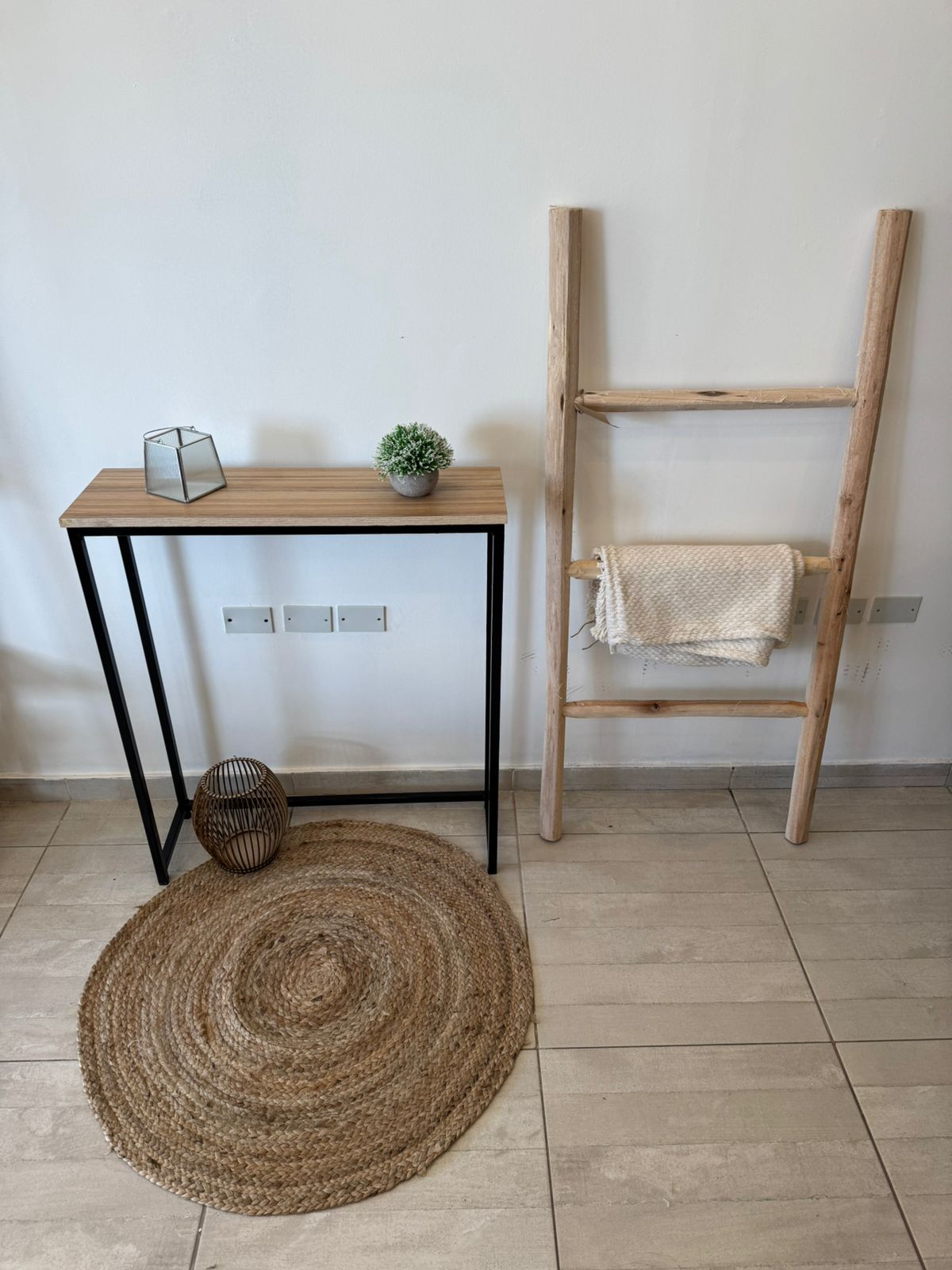 Habitación minimalista con estantería de escalera de madera, mesa pequeña, alfombra tejida.