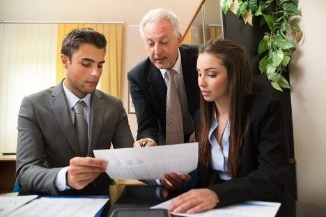 two men and a woman looking at a document