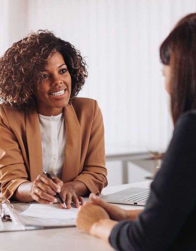 A woman is sitting at a table talking to another woman.