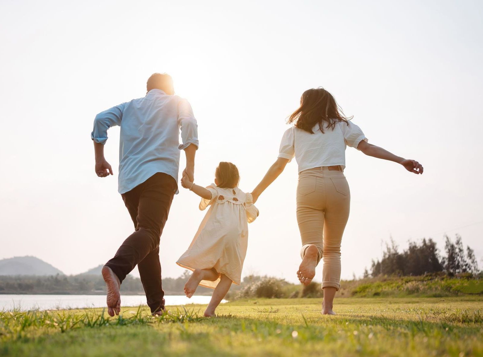 A family is running in a field holding hands.